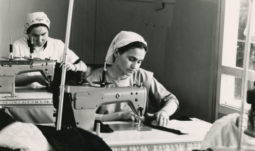 This is a black-and-white photograph taken by Maya Pejić in 1986 of two Turkish women sitting at a sewing machine in a textile factory.